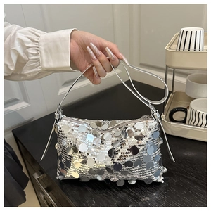 Detailed view of a silver sequined handbag held by a hand in a stylish setting