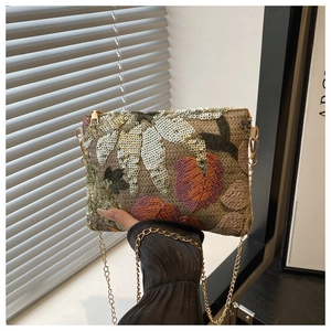 Detail of embroidered floral handbag with silver sequins and golden chain strap