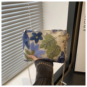 Detail showing 3D floral embroidery with sequins and golden chain on the white woven bag