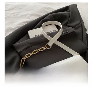 Dettaglio della borsa a tracolla bianca in pelle con catena d'oro su blazer nero