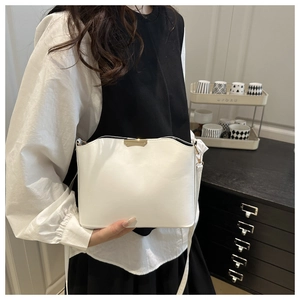Detail of minimalist white leather shoulder bag with elegant gold buckle and curved edge
