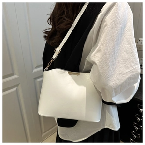 Detailed side view of white faux leather crossbody bag with elegant gold metal trim