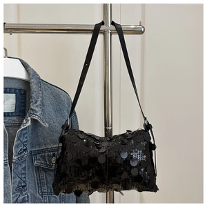 Detail of black sequined shoulder bag with adjustable strap on a hanger