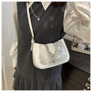 Détail du sac baguette à paillettes blanches avec boucle dorée porté à l'épaule