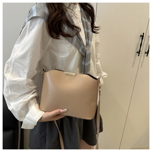 Detail view of a minimalist beige bucket bag with smooth leather and gold metal trim