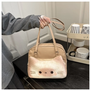 Close-up of cat-shaped plush pocket and embroidery details on a light brown leather bag