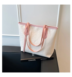 Détails des motifs gaufrés sur le cabas en cuir blanc avec finitions roses