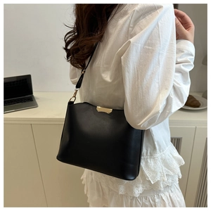 Detail view of black saddle bag with elegant gold metal trim and smooth leather texture