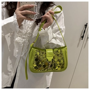 Détail du sac baguette vert néon avec de grands sequins dorés et boucle en métal