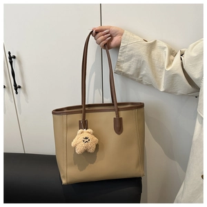 Close-up of khaki tote bag featuring dark brown handles and a yellow star plush charm
