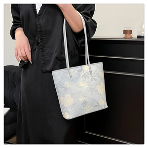 Close-up of floral pattern tote bag with silver hardware and grey shoulder straps