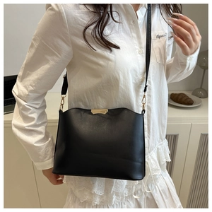 Detail of black faux leather bag with gold metal trim and adjustable strap in studio
