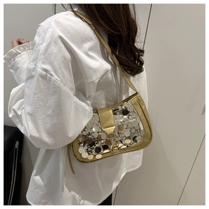 Gros plan du sac baguette à paillettes dorées avec bordure en cuir métallisé sur modèle