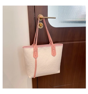 Détail du sac cabas beige avec anses roses et motifs de dessins animés gaufrés sur une porte