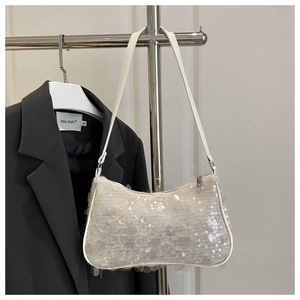 Macro detail of sparkly silver sequins and sleek white leather piping on a shoulder bag