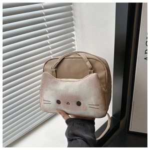 Detailed view of beige nylon cat crossbody bag held by hand near a sunlit window