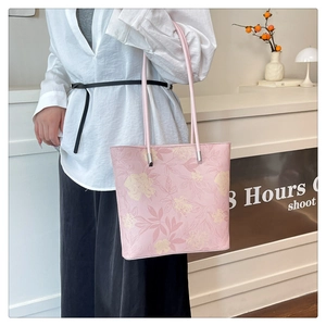 Pink floral tote bag with yellow flowers shown on a shoulder in a lifestyle setting