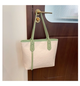 Détail des motifs gaufrés floraux et cartoon sur le sac cabas beige avec bord vert