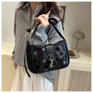 Détails des paillettes noires brillantes et du fermoir doré sur ce sac baguette chic