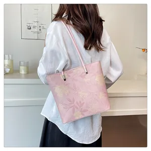 Detail of light pink tote bag with floral prints shown on a shoulder in a cafe setting