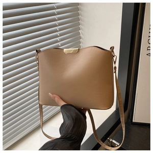 Detail view of beige PU leather bucket bag with gold metal trim and adjustable strap