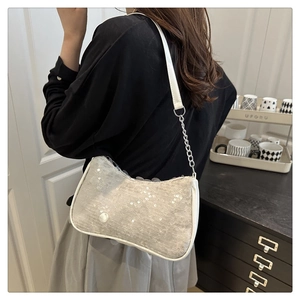 Detail of light gray sequined shoulder bag with white piping and chain strap on a model