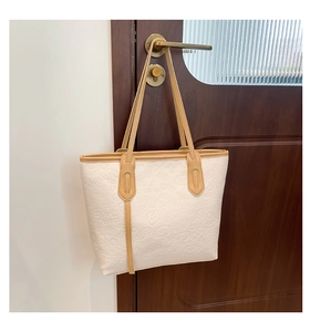 Détail du cabas en cuir blanc avec motifs gaufrés raffinés et bandoulières marron clair