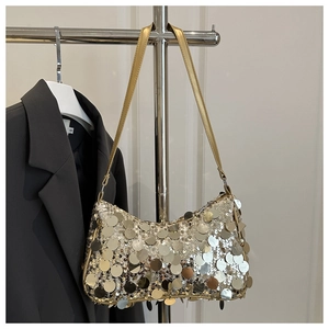 Close-up of golden sequins on a large shoulder bag hanging next to a blazer