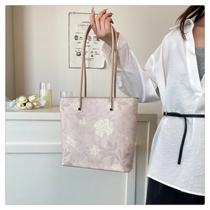Close-up of pink tote bag with white floral embroidery and slim leather shoulder straps