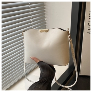 Detail of white PU leather bucket bag with gold metal trim and adjustable strap