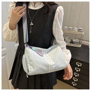Detail of light blue oxford dumpling bag featuring contrast stripes and purple zipper pull