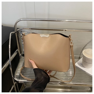 Close-up of khaki shoulder bag with wavy edge and silver metal buckle on modern shelf
