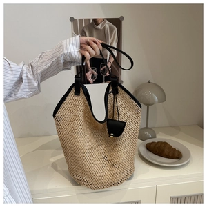 Detail of hand-woven straw tote bag with black trim and matching leather coin purse