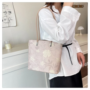 Detail view of pink tote bag with yellow floral pattern on model in cozy interior