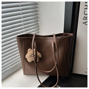Close-up of deep brown tote bag on window sill with soft lighting and plush star charm