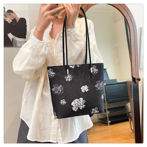 Detail of black tote bag with white floral line art and silver metal strap connectors