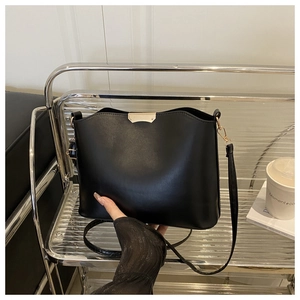 Detail of black PU leather shoulder bag with wavy top edge and gold metal fastener