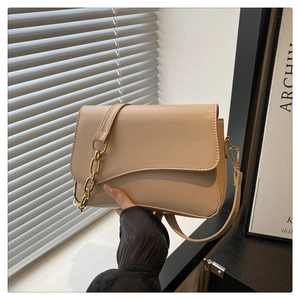 Dettaglio borsa a tracolla beige con patta a onde e catena dorata a maglie