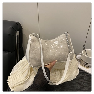 Close-up of beige sequin hobo bag with white leather trim and silver chain detail