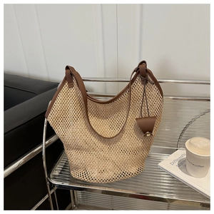Detail of woven straw tote bag with brown leather trim and hanging pouch on a shelf