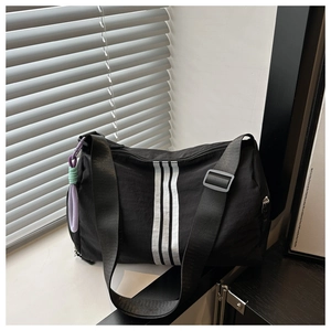 Detail of black striped shoulder bag showing wide adjustable strap and colorful lanyard