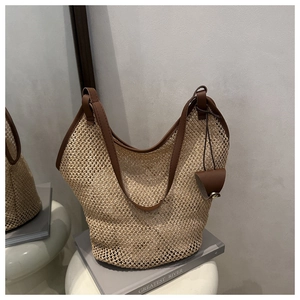 Detail of hand-woven straw tote with premium brown leather handles and side charm