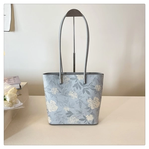 Detailed close-up of light blue floral tote bag with grey straps and elegant embroidery