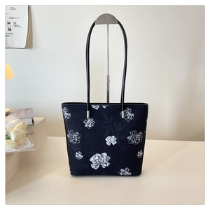 Detail of minimalist tote bag with white floral pattern on black fabric and metal hardware
