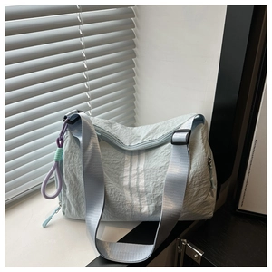 Detailed shot of mint green nylon sports bag featuring white stripes and woven charm