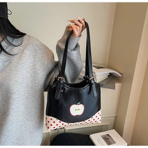 Dettaglio della borsa tote in pelle PU nera con motivo a mela e finiture a pois retrò