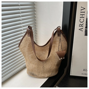 Detail of hollow woven straw bag with dark brown leather trim and handles for summer