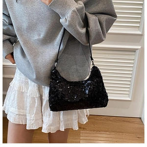 Detail of a black sequin crescent hobo bag with reflective texture and minimalist strap