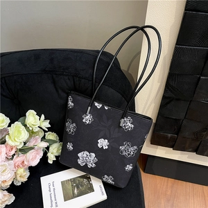 Chic floral tote bag with black faux leather straps on a vintage armchair