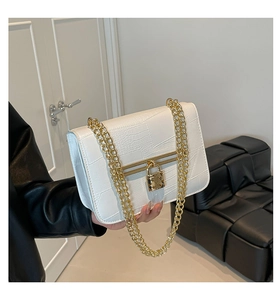 Close-up of white crocodile embossed texture and golden chain on a mini square bag
